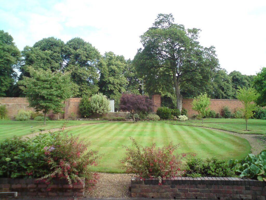 Záber na upravený trávnik a stromy v záhrade.